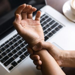 Woman holding her wrist pain from using computer.