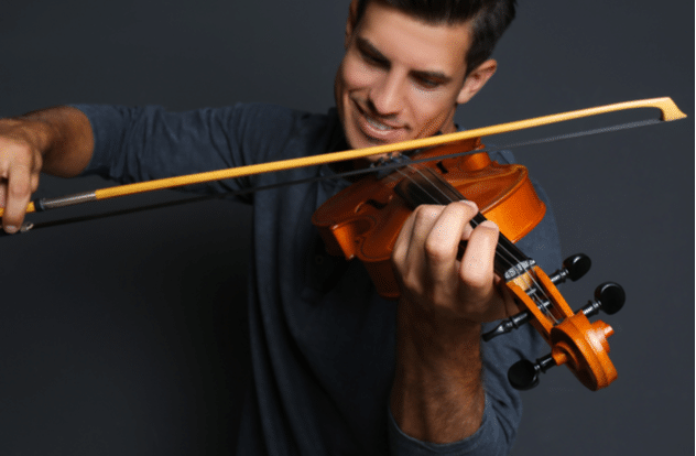 Happy man playing violin on focus on hand